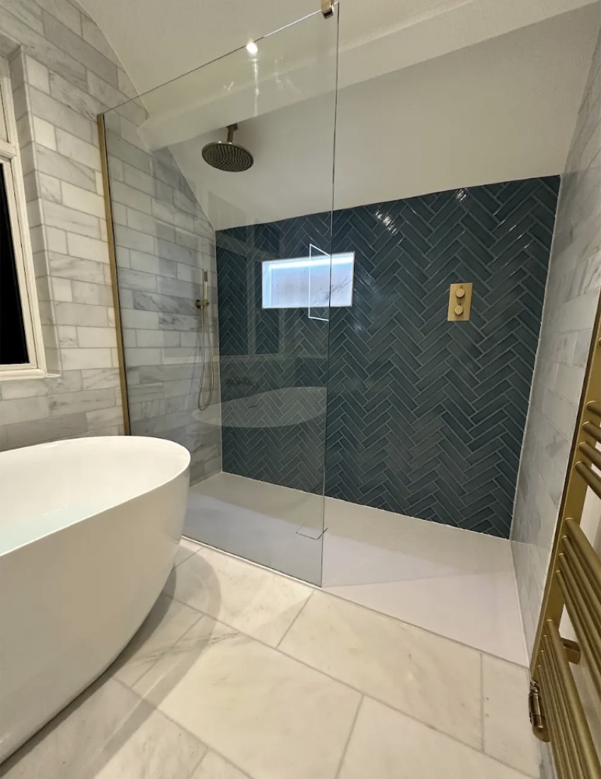 Bathroom with a blue herringbone shower wall, marble tiling, a freestanding bath and brushed brass fittings